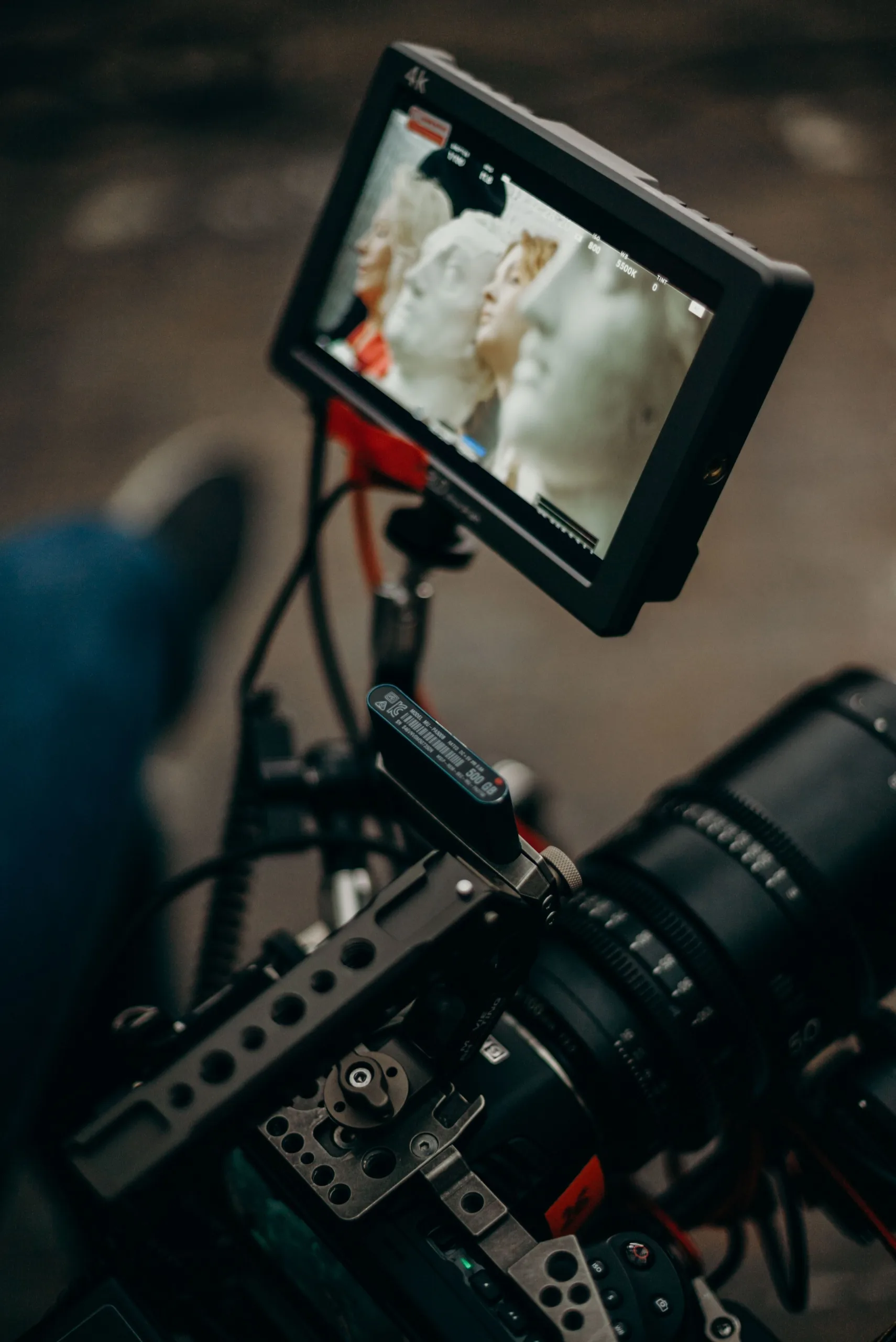 4K field monitor on a cinema camera rig showing footage of white classical statues during an outdoor shoot