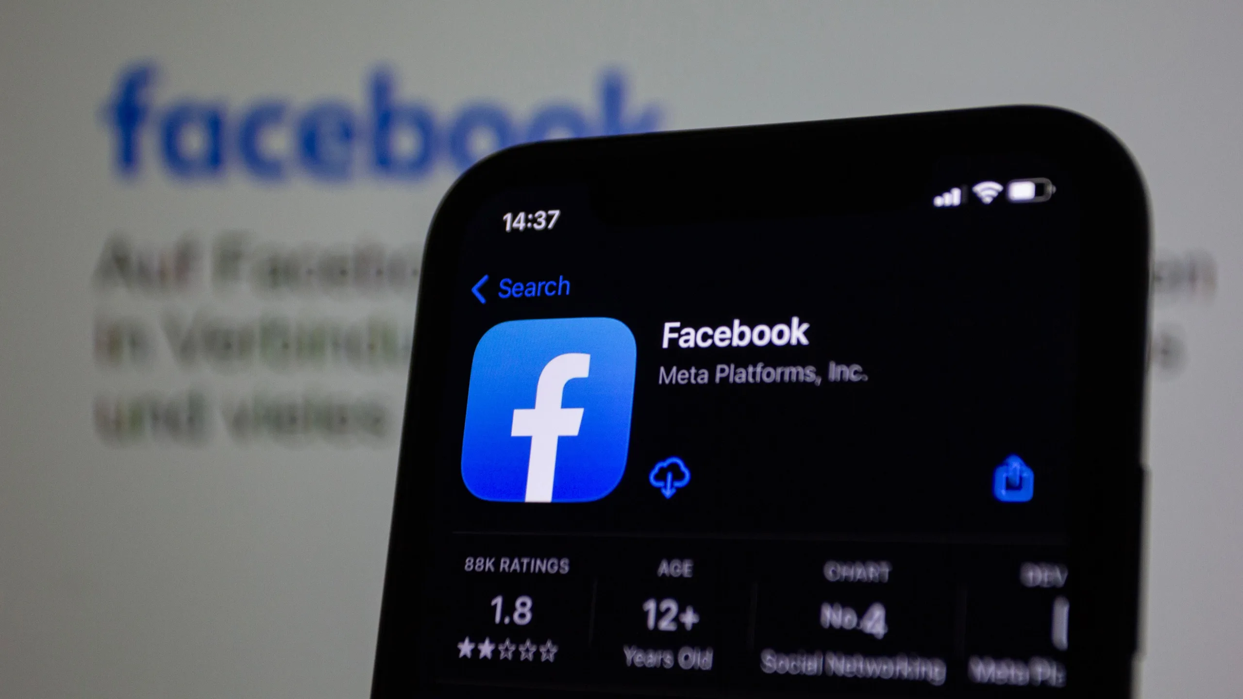Facebook app listing in the App Store on an iPhone, with the Facebook logo blurred in the background